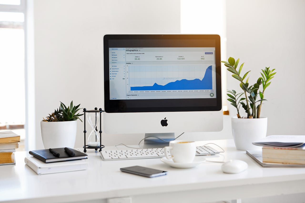 A clean, contemporary workspace featuring a desktop with analytics on the screen and plants for a fresh look.